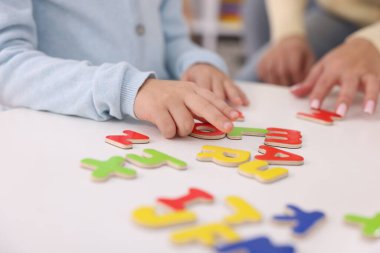Anne, kızına beyaz masada alfabe öğretiyor, yakın plan.