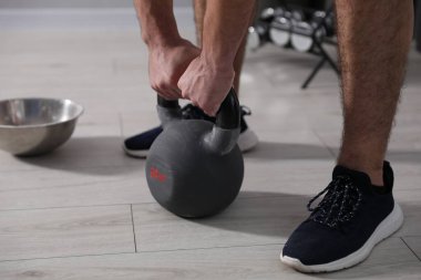Güçlü adam spor salonunda kettlebell ile egzersiz yapıyor, yakın plan.