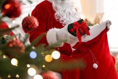 Noel Baba Noel ağacının yakınındaki çuvaldan hediyesini alıyor.