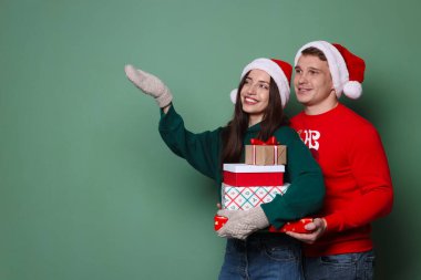 Yeşil arka planda Noel Baba şapkalı mutlu çift. Metin için boşluk