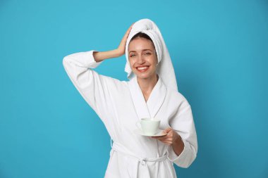 Bornozlu kadın açık mavi arka planda bir fincan kahveyle