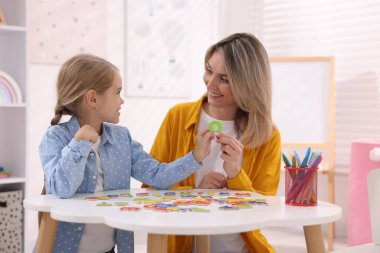 Anne, kızına beyaz masada alfabe öğretiyor.