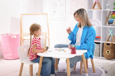 Anne, kızına beyaz masada alfabe öğretiyor.