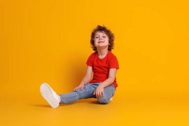 Turuncu arka planda küçük şirin bir çocuğun portresi.