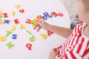 Beyaz masada harflerle alfabeyi öğrenen küçük kız, yakın plan.