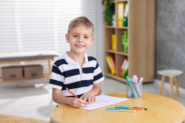 İçerideki ahşap masada resim yapan sevimli küçük çocuk. Metin için boşluk