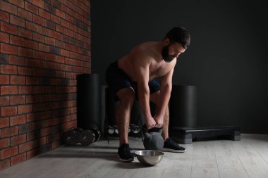 Spor salonunda kettlebell ile egzersiz yapan güçlü bir adam.