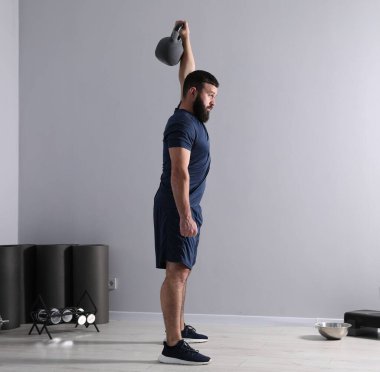 Spor salonunda kettlebell ile egzersiz yapan güçlü bir adam.
