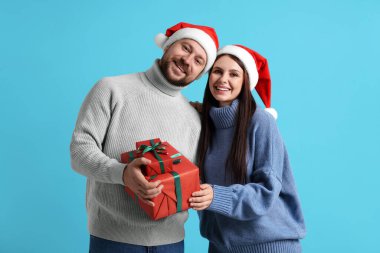 Açık mavi arka planda Noel hediyeli mutlu çift