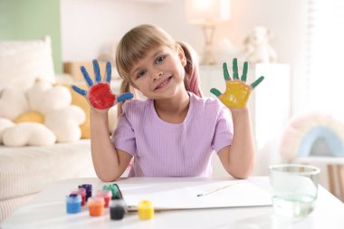 Beyaz masalarda avuç içleri çizen sevimli küçük kız.