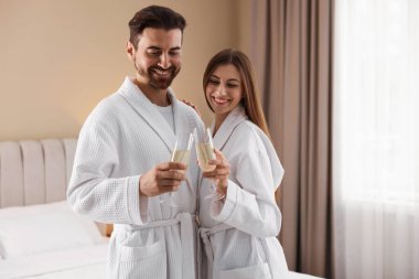 İçeride köpüklü şarap bardakları olan bornozlu mutlu bir çift. Metin için boşluk