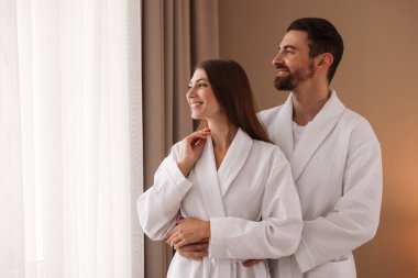 Otel odasında bornoz giyen mutlu çift. Metin için boşluk