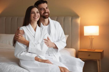 İçerideki yatakta bornozlu mutlu çift. Metin için boşluk