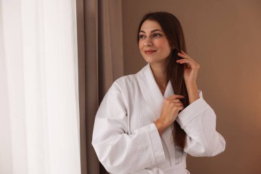 Otel odasının penceresinin yanında beyaz bornoz giyen güzel bir kadın. Metin için boşluk