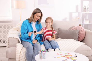 Anne, kızına beyaz masada alfabe öğretiyor.