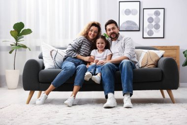 Mutlu ebeveynler evdeki kanepede kızlarına sarılıyorlar. Aile bağı