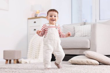 İlk adımlar. Evinde yerde yürüyen sevimli küçük bebek.