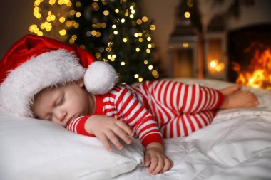 Noel pijamalı bebek ve Noel Baba şapkalı evde uyuyan bebek.