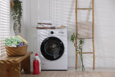 Modern çamaşır makinesi, deterjanlar, ev bitkileri ve iç çamaşırları.