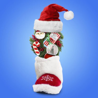 Noel çelengi ve diğer dekorlar mavi arka planda kırmızı çizmeye düşüyor.