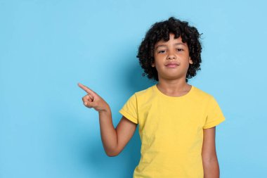 Açık mavi arkaplanı işaret eden küçük çocuğun portresi