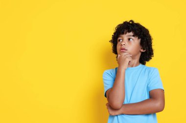 Sarı arka planda düşünceli küçük bir çocuğun portresi, mesaj için boşluk.