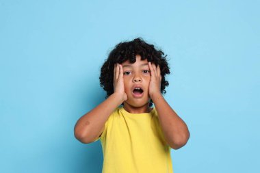 Açık mavi arka planda şaşırmış küçük bir çocuğun portresi