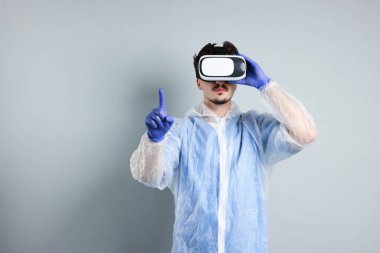 Modern teknoloji. Gri arka planda sanal ekran kullanan kulaklıklı bir doktor. Metin için boşluk