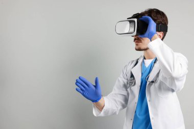 Modern teknoloji. Doktor gri arka planda sanal gerçeklik kulaklığı kullanıyor. Metin için boşluk