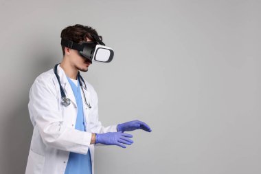 Modern teknoloji. Doktor gri arka planda sanal gerçeklik kulaklığı kullanıyor. Metin için boşluk