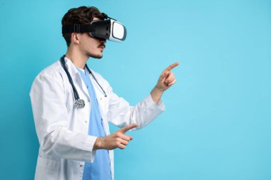 Modern teknoloji. Açık mavi arka planda sanal ekran kullanan kulaklıklı bir doktor. Metin için boşluk