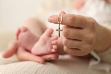 Vaftiz ayini. Kadın kucağında küçük bebek ve altın haç, seçici odaklanma