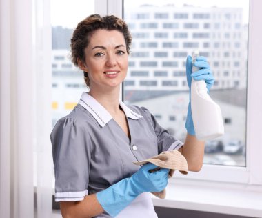 Pencereyi temizliyorum. İçeride bez ve deterjanı olan oda hizmetçisi.