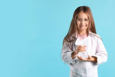 Laboratuvar önlüğü ve açık mavi arka planda mataralı gözlüklü şirin küçük kız, mesaj için yer var. Çocuk ve bilim