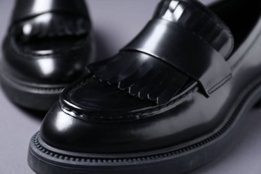 Gri arka planda şık siyah ayakkabılar, yakın plan.