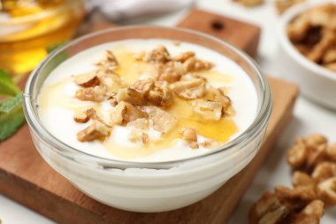 Delicious Greek yogurt with honey and walnuts served on white table, closeup