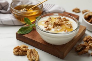 Delicious Greek yogurt with honey and walnuts served on white table, closeup