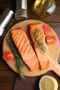 Lezzetli ızgara somon, biberiye, domates ve baharatlar ahşap masada, düz yerde.