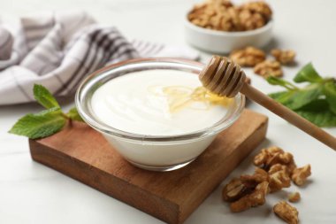 Delicious Greek yogurt with honey and walnuts served on white table, closeup