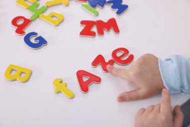 Beyaz masada harflerle alfabeyi öğrenen küçük kız, yakın plan.