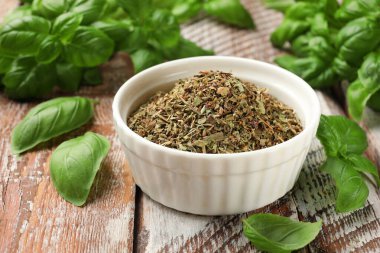 Kuru fesleğen yaprakları, taze olanlar ve renkli ahşap masa, yakın plan.