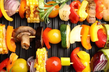 Skewers with tasty vegetables on grill pan, top view