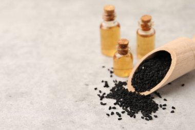 Açık gri masada siyah kimyon tohumları ve yağ, yakın plan. Metin için boşluk