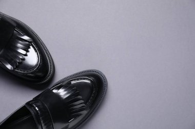 Gri arka planda bir çift şık siyah mokasen ayakkabı, düz. Metin için boşluk
