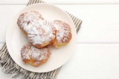 Beyaz ahşap masa üzerinde pudra şekerli lezzetli profiteroller, üst manzara. Metin için boşluk