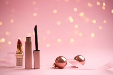 Bulanık ışıklı pembe arka planda makyaj ürünleri ve Noel dekoru, bokeh etkisi