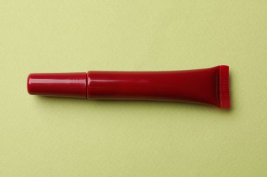 Açık yeşil arkaplanda koyu kırmızı dudak parlatıcısı.