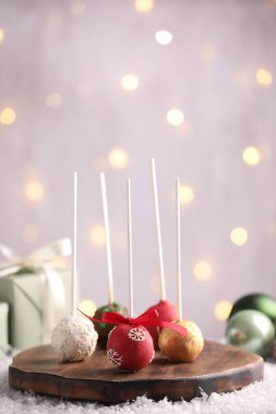 Yapay kar üzerine serpiştirilmiş, gri arkaplanlı, bulanık ışıklı, yakın plan şekerli kek. Noel atıştırması