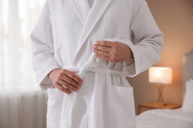 Bornozun kemerini bağlayan adam içeride, yakın plan.