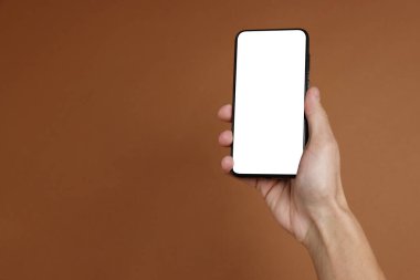 Kahverengi arka planda boş ekranlı akıllı telefon tutan adam, yakın plan. Tasarım için model
